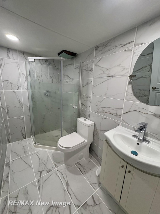 bathroom with vanity, tile walls, an enclosed shower, and toilet