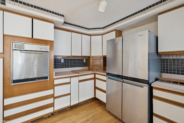 kitchen with backsplash, white cabinets, and appliances with stainless steel finishes