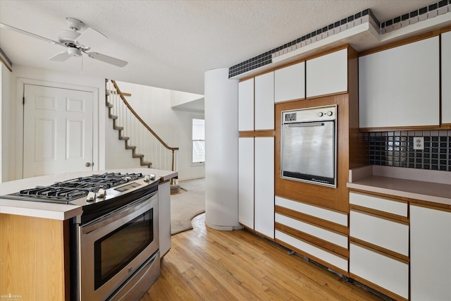 kitchen with white cabinetry, tasteful backsplash, a textured ceiling, stainless steel appliances, and light hardwood / wood-style floors