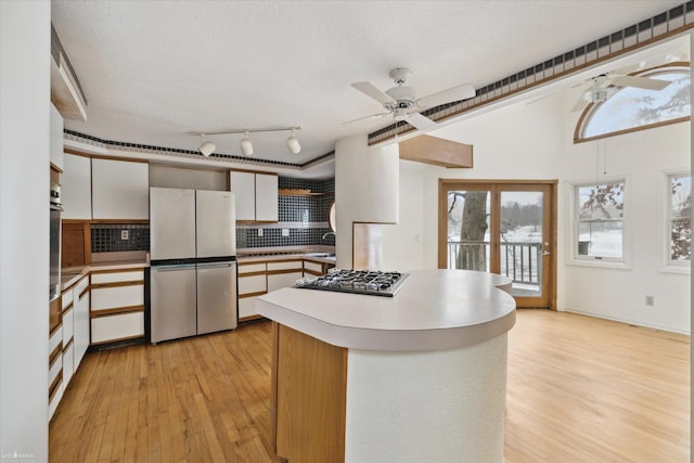 kitchen with appliances with stainless steel finishes, white cabinets, and light wood-type flooring