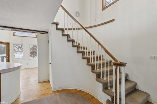 stairs featuring a healthy amount of sunlight and hardwood / wood-style floors