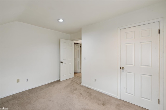 unfurnished bedroom with light colored carpet and lofted ceiling