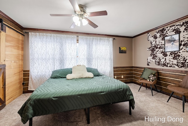 carpeted bedroom with ornamental molding, a barn door, ceiling fan, and wood walls