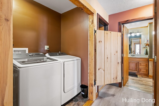 washroom with washing machine and clothes dryer, light hardwood / wood-style floors, and a textured ceiling