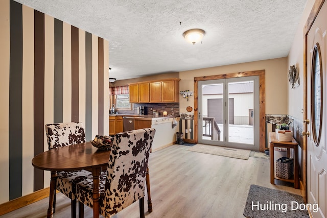 dining room with sink, light hardwood / wood-style floors, and a textured ceiling