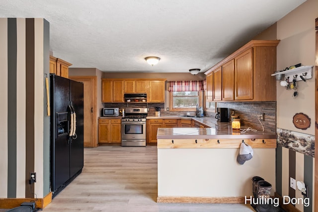 kitchen featuring decorative backsplash, light hardwood / wood-style floors, kitchen peninsula, stainless steel appliances, and a textured ceiling