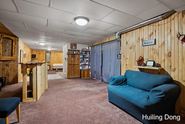 sitting room with a paneled ceiling, wooden walls, and carpet floors