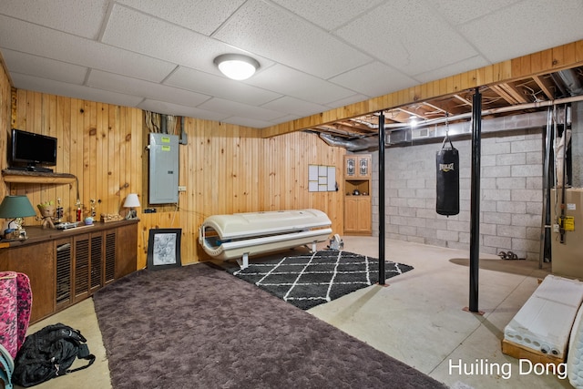 bedroom with wooden walls, electric panel, and concrete floors