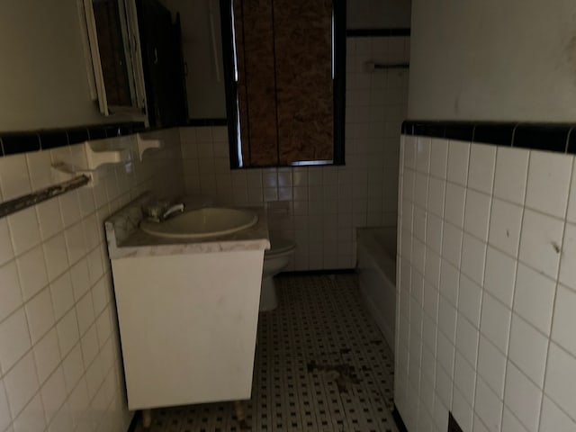 bathroom featuring a bathing tub, sink, tile walls, and toilet