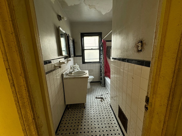 full bathroom with shower / tub combo with curtain, vanity, toilet, and tile walls