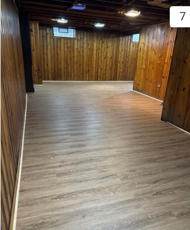 basement featuring light hardwood / wood-style flooring and wood walls