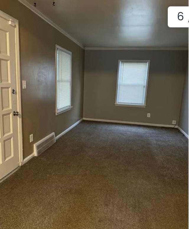 spare room featuring dark colored carpet and ornamental molding