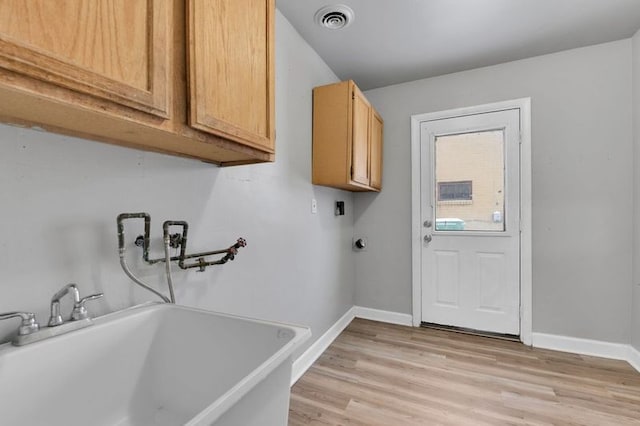 washroom with cabinets, electric dryer hookup, and light hardwood / wood-style flooring