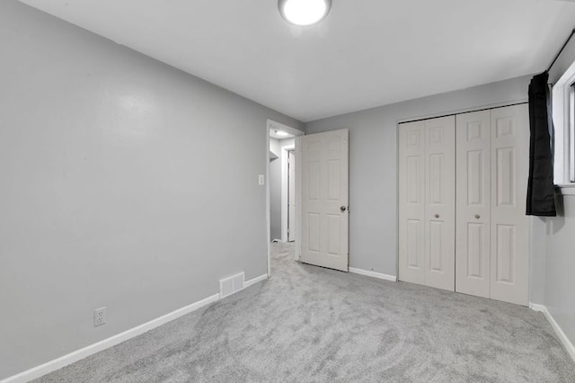 unfurnished bedroom featuring light carpet and a closet