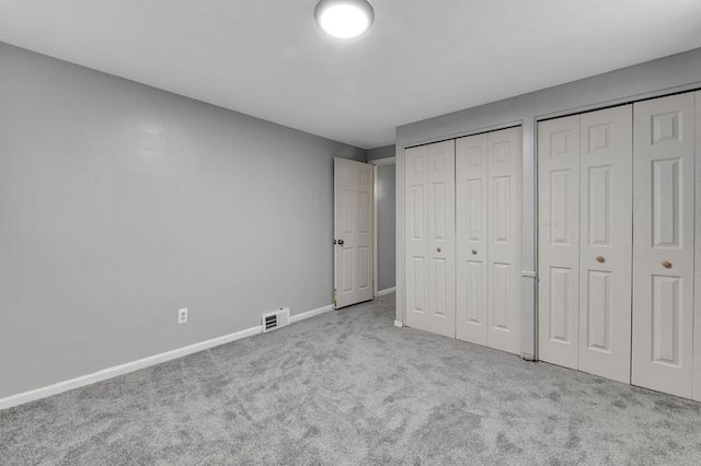 unfurnished bedroom with two closets and light colored carpet