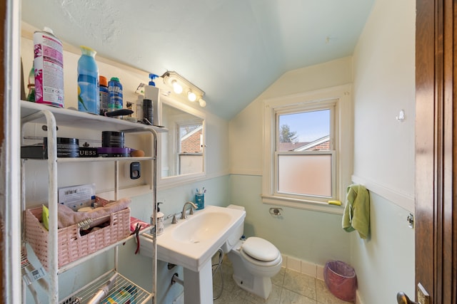 bathroom with lofted ceiling, sink, tile patterned flooring, and toilet