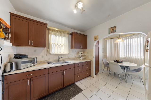 kitchen featuring sink, light tile patterned floors, decorative backsplash, and decorative light fixtures