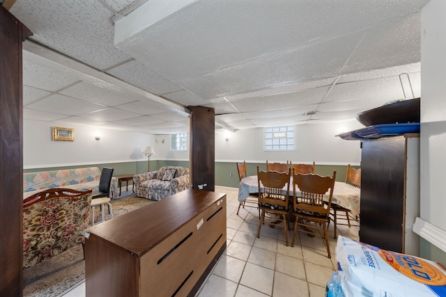 tiled dining space featuring a drop ceiling