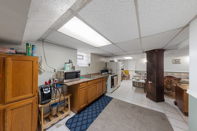 kitchen featuring light tile patterned floors, sink, white gas range oven, and a drop ceiling