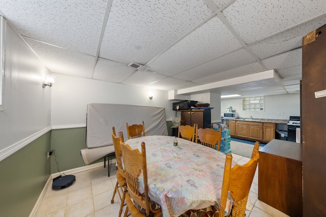 dining area featuring sink, a paneled ceiling, and light tile patterned flooring