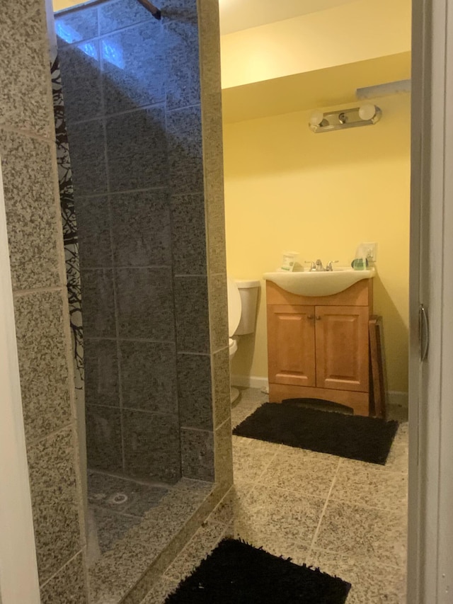 bathroom with tiled shower, vanity, toilet, and tile patterned floors