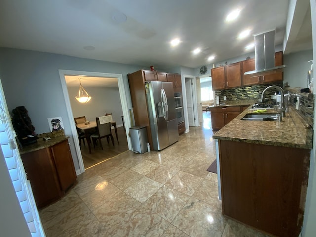 kitchen featuring pendant lighting, island range hood, sink, stainless steel fridge, and backsplash