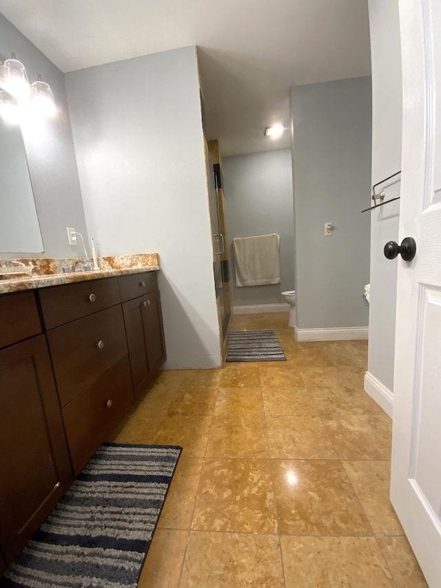 bathroom with vanity, a shower with shower door, and toilet