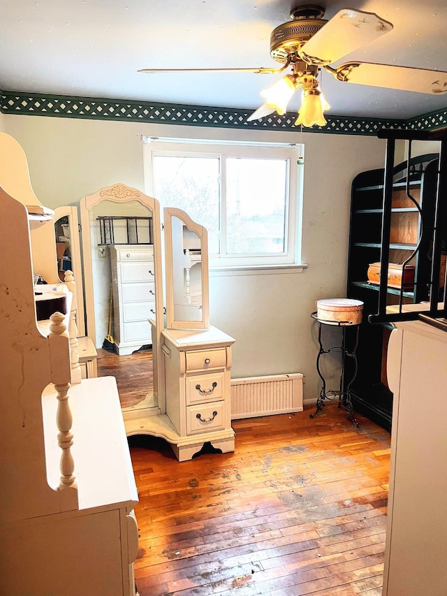 bedroom featuring wood-type flooring and a baseboard radiator