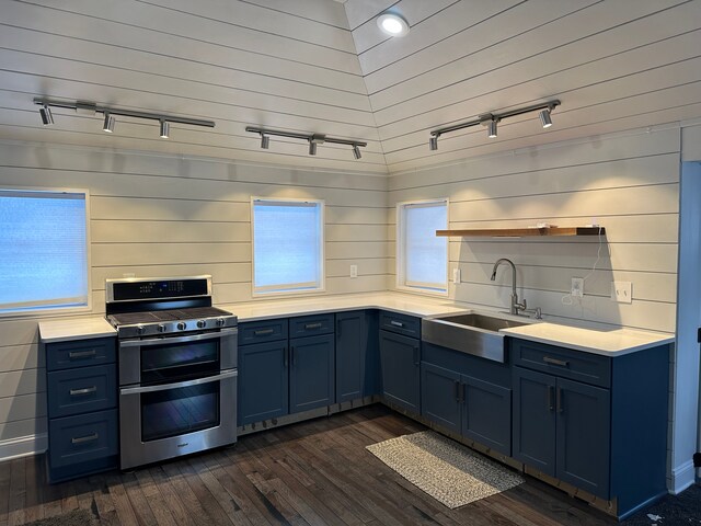 kitchen with blue cabinetry, rail lighting, sink, dark hardwood / wood-style flooring, and range with two ovens