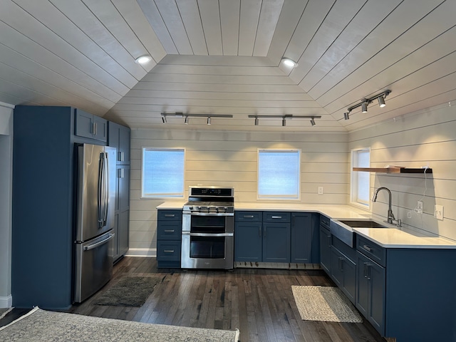 kitchen featuring dark hardwood / wood-style floors, lofted ceiling, sink, stainless steel appliances, and blue cabinetry