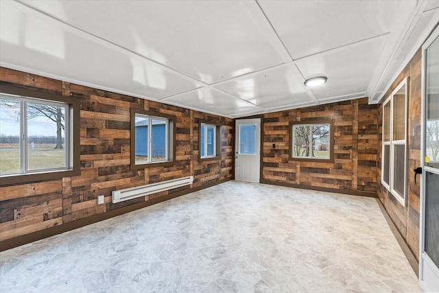 unfurnished living room featuring a baseboard heating unit and wood walls