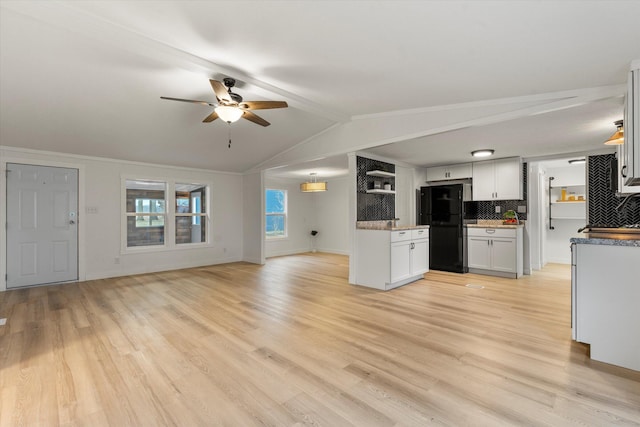 kitchen featuring tasteful backsplash, light wood-type flooring, white cabinets, and black fridge