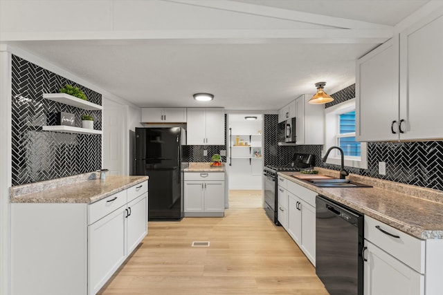 kitchen with sink, white cabinets, decorative backsplash, light hardwood / wood-style floors, and black appliances