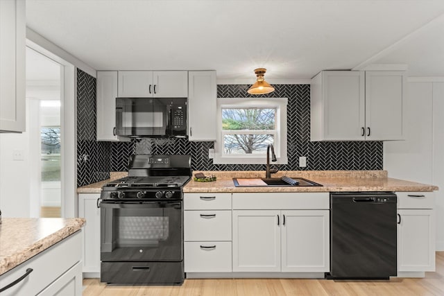 kitchen with sink, white cabinetry, black appliances, light hardwood / wood-style flooring, and backsplash