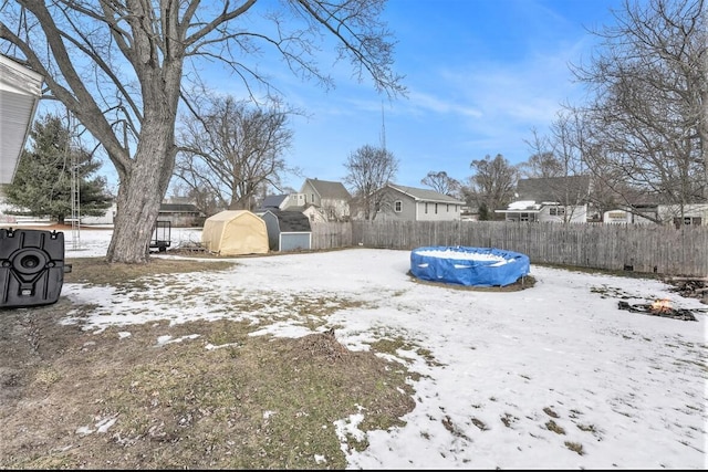 yard layered in snow featuring a covered pool and a shed