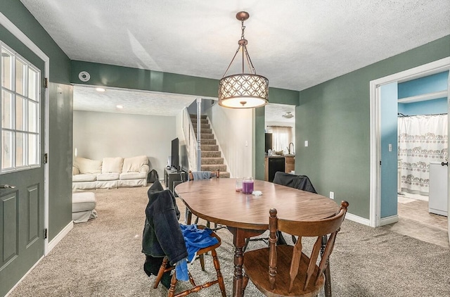 dining area with light colored carpet and a textured ceiling