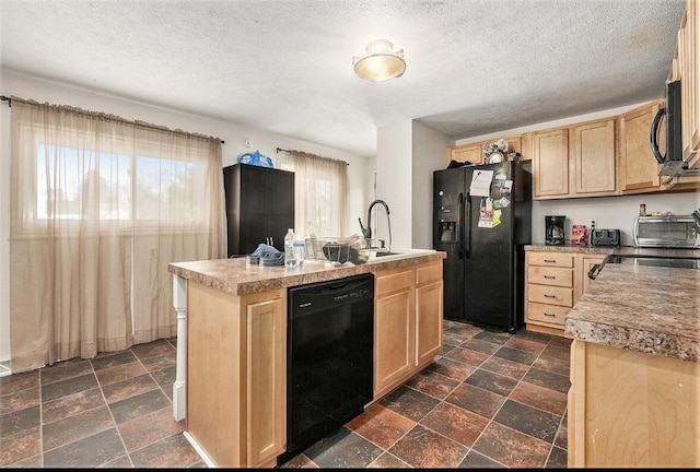 kitchen featuring sink, a textured ceiling, light brown cabinets, a center island with sink, and black appliances