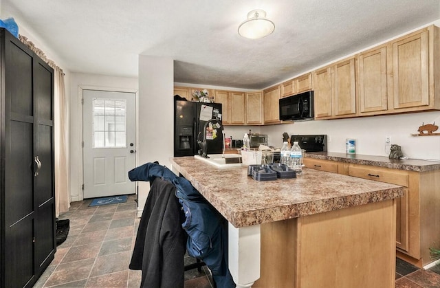 kitchen with a breakfast bar area, black appliances, a textured ceiling, a kitchen island, and light brown cabinetry