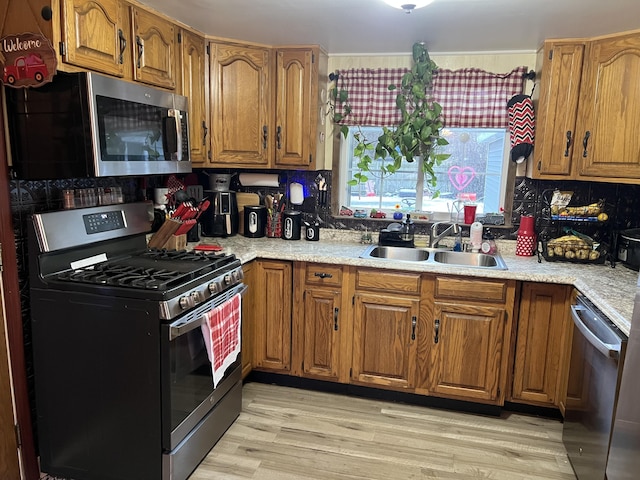 kitchen featuring stainless steel appliances, sink, backsplash, and light wood-type flooring