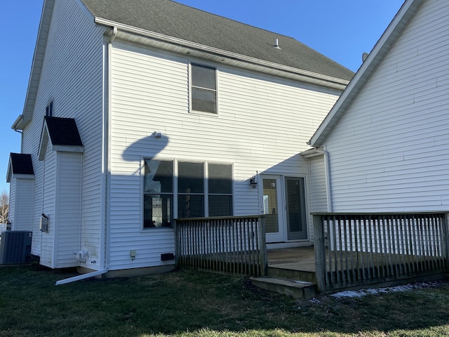 rear view of property featuring cooling unit, a deck, and a lawn