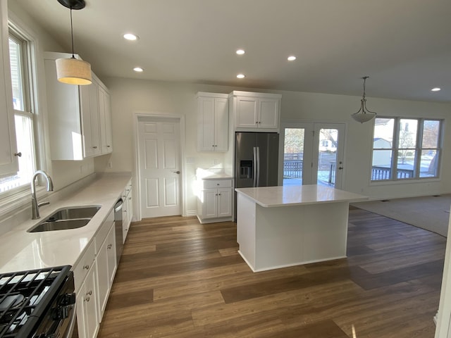 kitchen with decorative light fixtures, sink, white cabinets, gas stove, and stainless steel refrigerator with ice dispenser