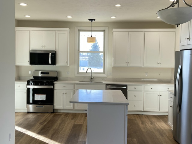 kitchen with sink, appliances with stainless steel finishes, hanging light fixtures, a center island, and white cabinets