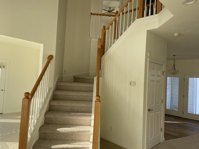 stairs with a towering ceiling and wood-type flooring