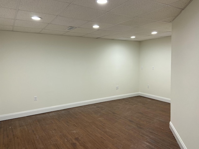 empty room with dark wood-type flooring and a drop ceiling