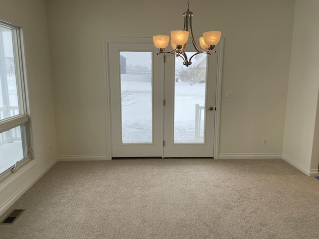 carpeted spare room with a notable chandelier