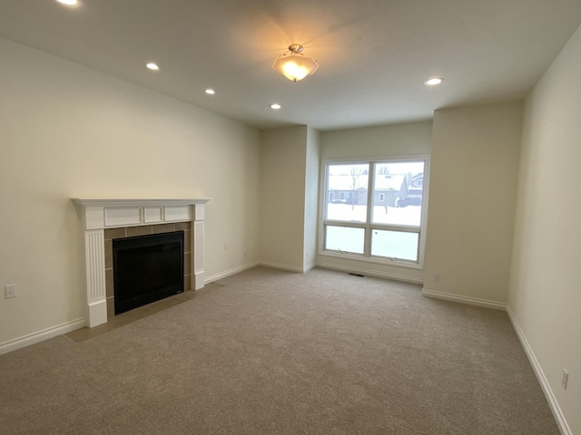 unfurnished living room featuring a tiled fireplace and light carpet