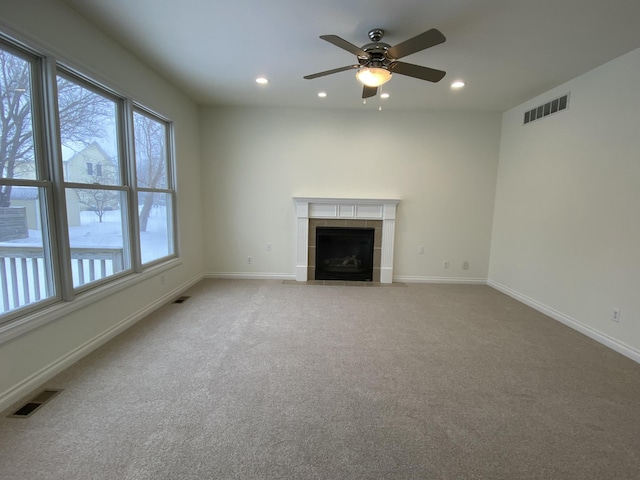 unfurnished living room with a fireplace, ceiling fan, and carpet