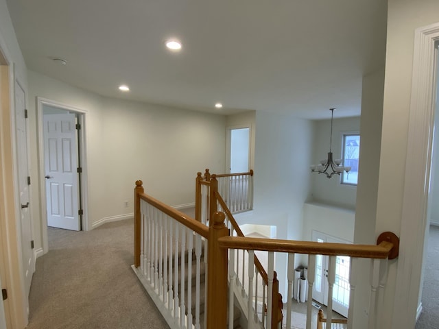 hall featuring light colored carpet and a notable chandelier