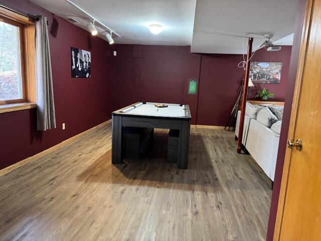 game room with hardwood / wood-style floors and track lighting