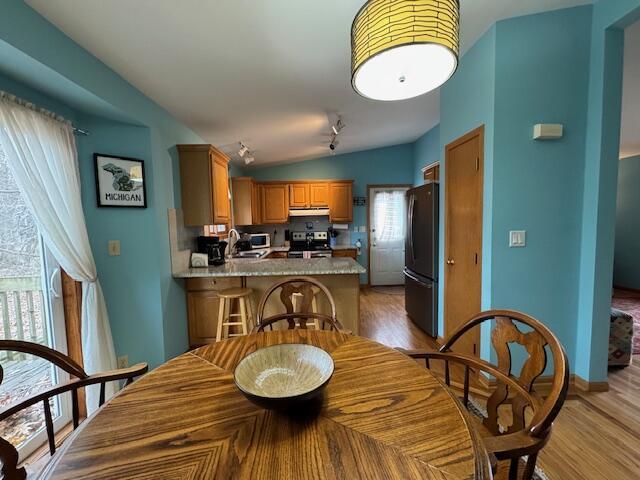 dining area with lofted ceiling, sink, and light hardwood / wood-style floors